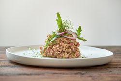 Plate with delicious steak tartar on wooden table