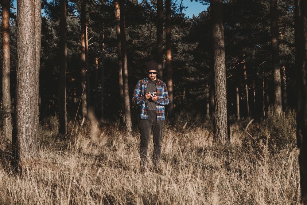 Confident photographer taking picture with camera in sunny forest