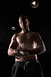 Muscular sportsman preparing hands with chalk for exercise