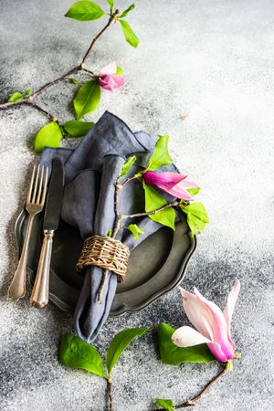 Top view of dark plate with magnolia flowers on grey counter