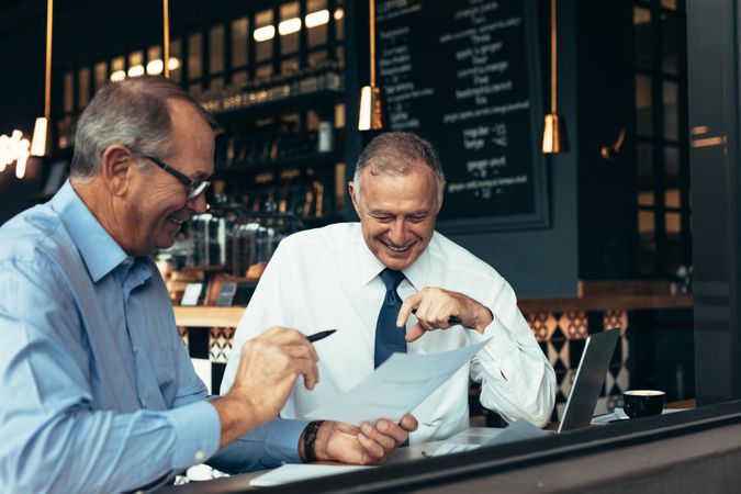 Two business partners reviewing contract papers at a restaurant
