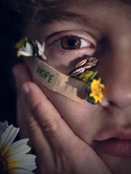 Crop boy with colorful flowers on cheek