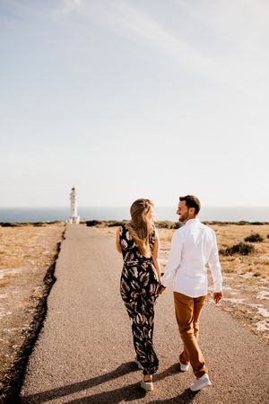 Smiling lovers cuddling on path to sea