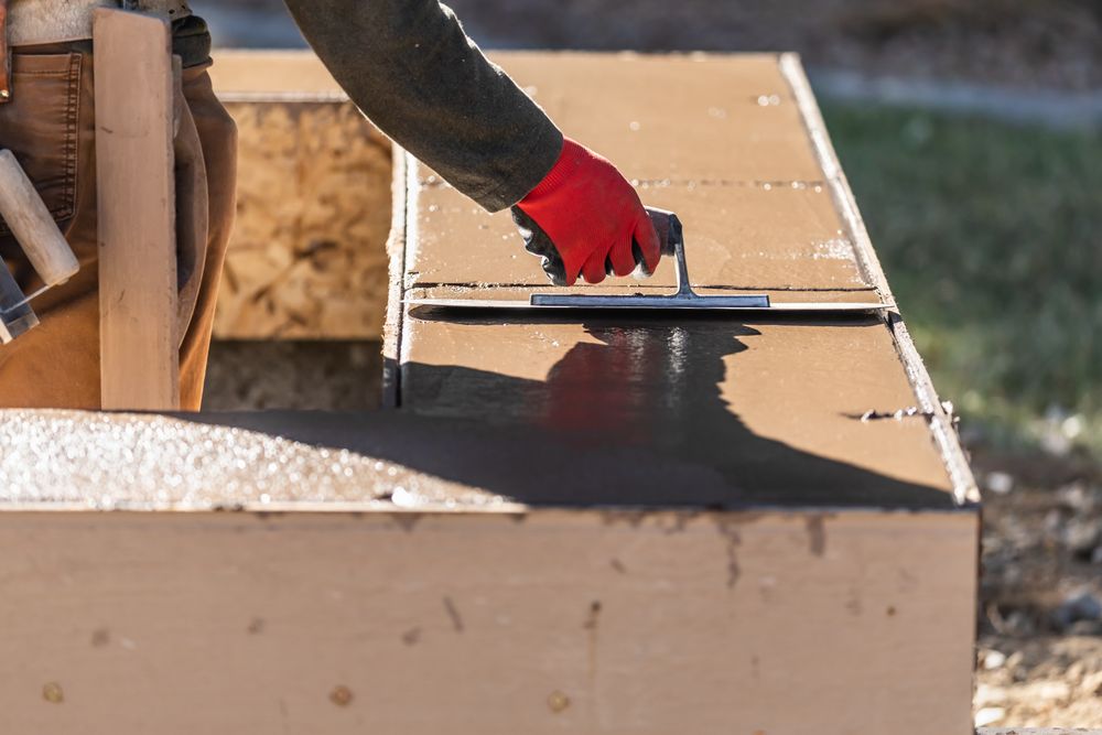 Construction Worker Using Trowel On Wet Cement Forming Coping Around New Pool