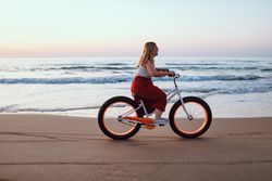 Joyful woman riding bicycle along peaceful beach