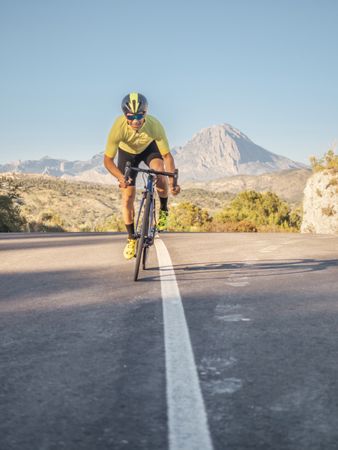 healthy man riding a bicycle on a mountain road in a sunny day