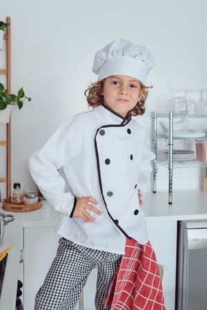 Confident boy in cook uniform in kitchen