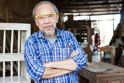 Man in safety glasses and plaid shirt in woodshop