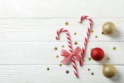 Candy canes and christmas accessories on wooden background, space for text