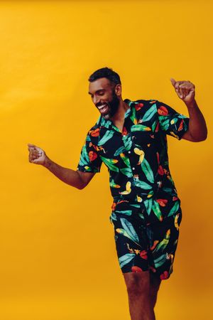 Happy male dancing in brightly patterned shirt and shorts