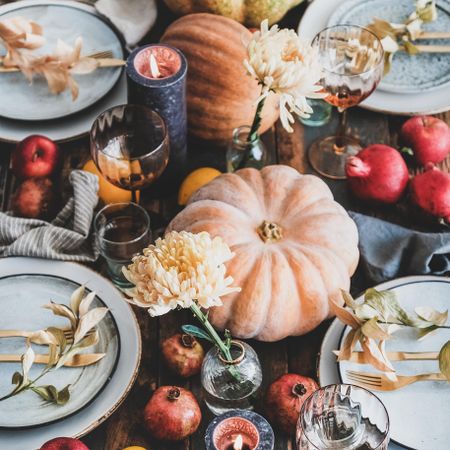 Fall table setting with squash, candles and pomegranates, square crop