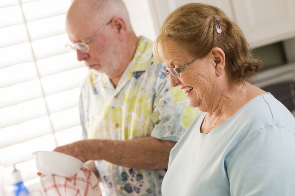 Older Adult Couple Washing Dishes Together Inside Kitchen