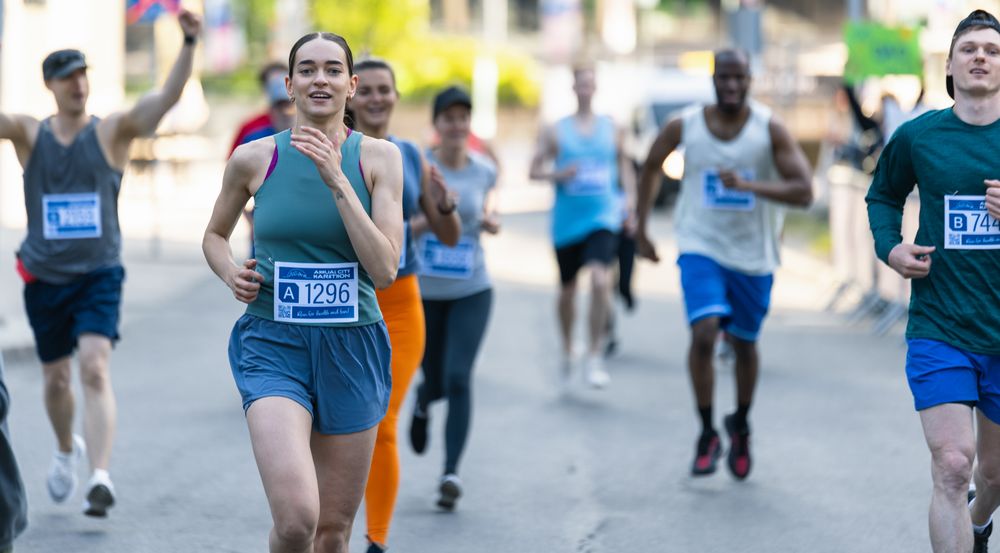 Diverse Group of People Running a Marathon in a City During the Day.