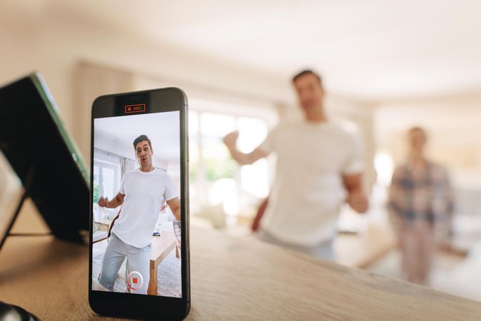Man dancing in front of a mobile phone with family at the back