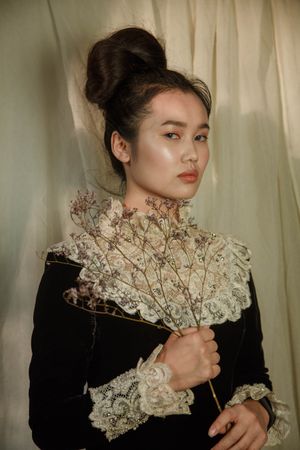 Portrait of East Asian woman with bun hairstyle holding dried flowers