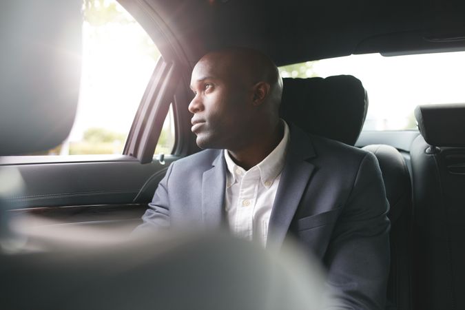 Businessman traveling to work in the luxury car in the back seat looking out