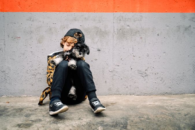 Lonely kid with small dog sleeping on street pavement