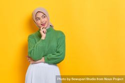 Woman in headscarf thinking and looking at yellow copy space 56mAe0