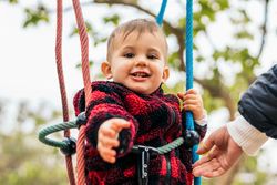 cute baby playing with his mother on a swing