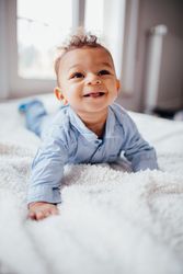 Smiling baby boy lying on his stomach with his head up