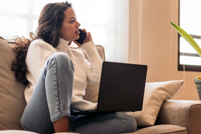Remote Work and Communication: Young Woman Using Laptop and Smart Phone at home