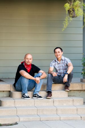 Portrait of two men in casual clothes sitting on their porch looking at their neighborhood
