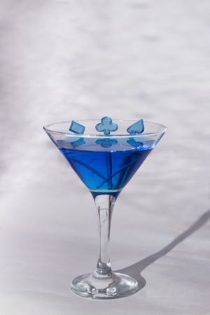 Blue cocktail in martini glass with card pips