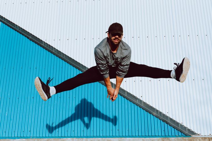 Trendy male flipping and jumping on street