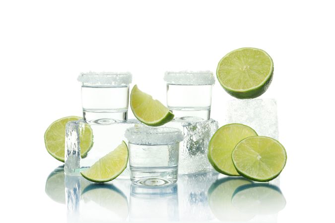 Ice cube pile with of lime halves and shot glasses