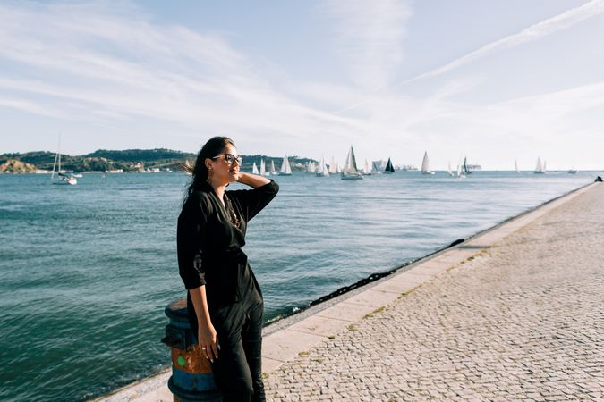 Stylish female holding hair and looking away on embankment