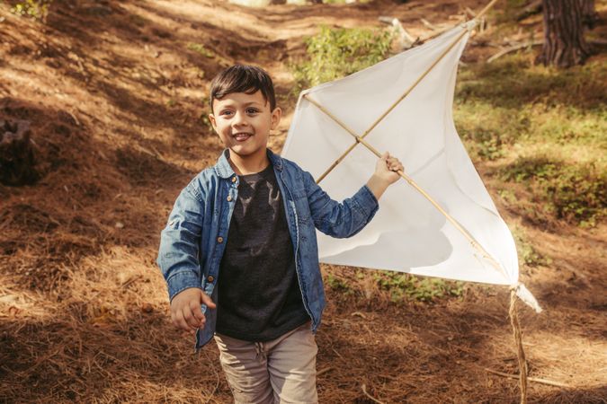 Cute boy running outdoors with a hand made kite