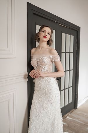 Magnificent pensive young bride in white lace dress looking at camera and pondering