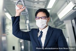 Businessman in facemask standing in metro car bDpBAb