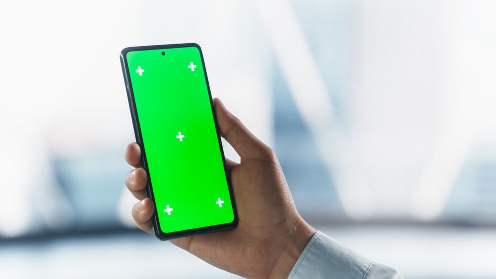 Businessman Holding a Smartphone Device, Looking at a Screen with Green Chromakey Mock Up Display. Photo Template with Motion Trackers for Digital Marketing, Website Design Demo, Advertising Campaign