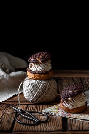 Delicious choux buns and wool threads on wooden table