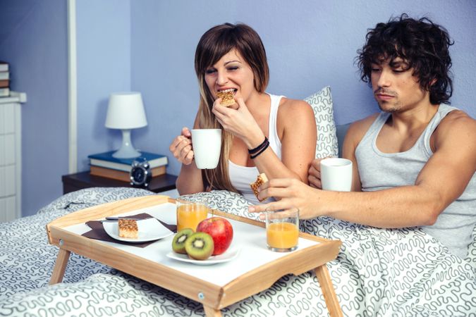 Couple having healthy breakfast in bed served over tray