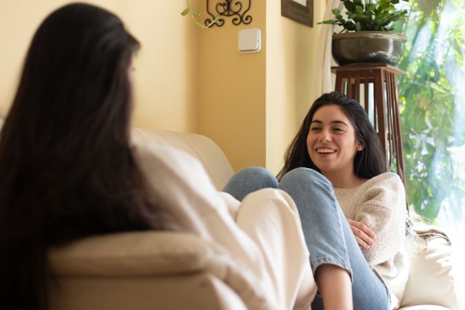 Smiling Young woman talking with her mother sitting on a sofa at home.