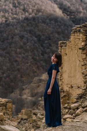 Side view of woman in long blue dress standing in natural landscape