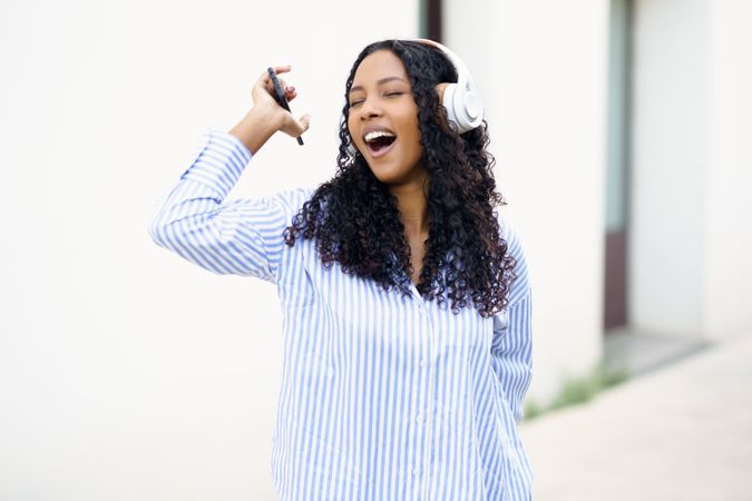 A Young Woman is Happily Enjoying Music While Wearing Headphones in an Outdoor Setting