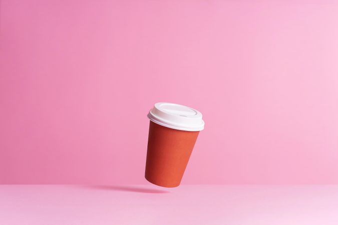 One disposable coffee cup on pink background