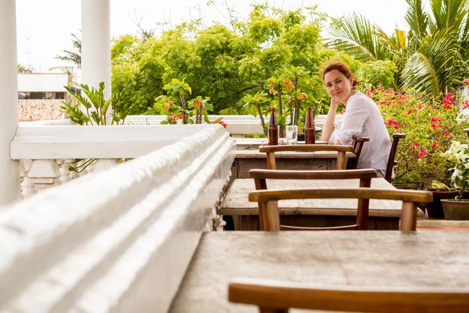 Smiling woman in outdoors cafe near tropical plants