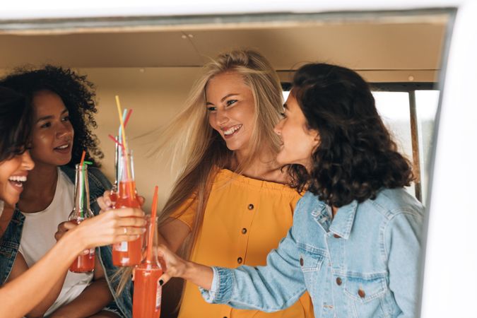 Diverse female friends toasting their drinks with straws