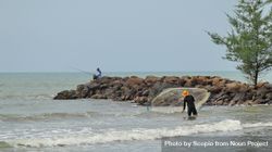 Two men fishing with fishing rod and net on the beach 4ZMVN5