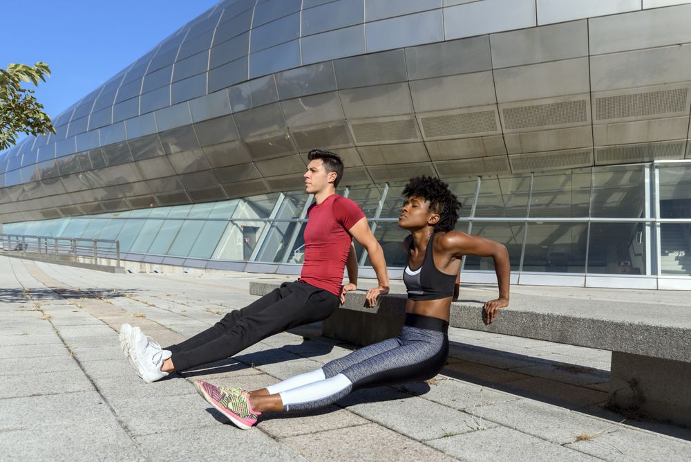Young sportive people doing push up exercises in city