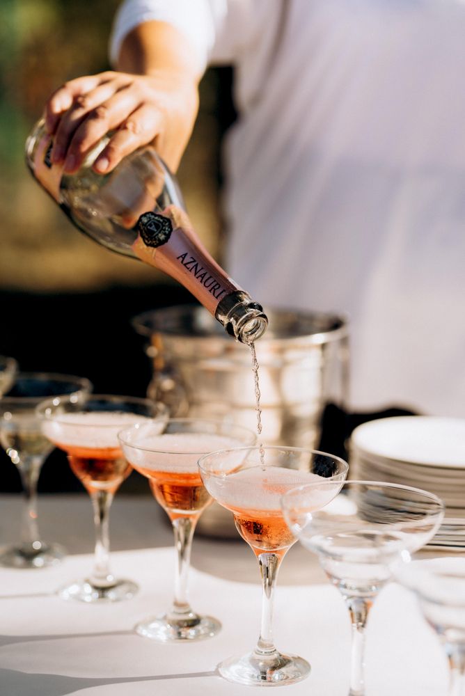 Person pouring sparkling wine in glasses