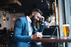 Man smiling at laptop during working lunch in a bar