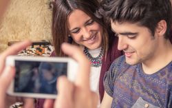 Male hands taking photos to couple on sofa