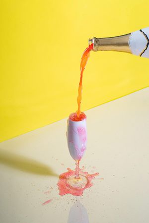 Rose champagne poured into glass against yellow background