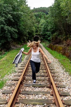 Woman walking along railway though greenery part of road