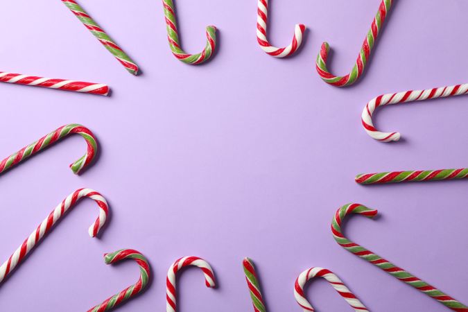 Composition with sweet candy canes on color background, space for text